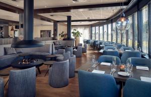 a restaurant with blue chairs and tables and windows at WestCord Hotel Noordsee in Nes