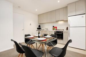 a kitchen with a table with chairs and a refrigerator at StayCentral on Lonsdale in Melbourne