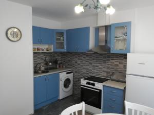 a kitchen with blue cabinets and a washing machine at Guest House Krasi in Ovoshtnik