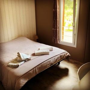 a bed with two towels on it next to a window at Chalet 2 chambres en Bois dans les landes n34 in Tosse +52 photos