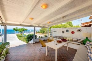 un patio con mesa, sillas y el océano en Kiko, the Coastline house, en Káto Achaḯa
