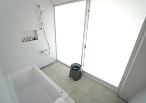 a white bathroom with a shower and a tub at Miru Amami in Tatsugo