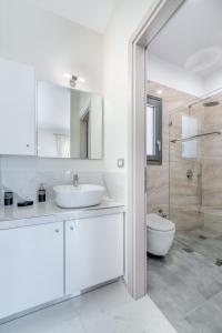 a white bathroom with a sink and a toilet at Kefalonia Stone Villas - Villa Petros Kefalonica in Trapezaki