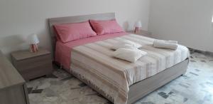 a bedroom with a large bed with pink and white sheets at Felline House in Manduria