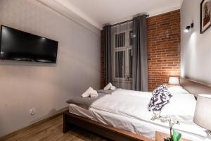 1 dormitorio con 1 cama y TV en la pared en Lubomirskiego 23 Residence - great location, 10 min to Main Square by foot, right next to Main Rail and Bus Station, en Cracovia