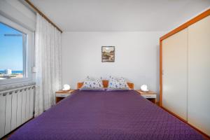 a bedroom with a purple bed with a window at Apartmani Patača in Vodice