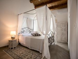 a bedroom with a white canopy bed with curtains at Ortigia Boutique Palace in Siracusa