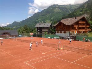 a group of people playing tennis on a tennis court at Chalet Courage in Champéry