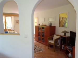a living room with an archway with a chair and a television at Gadahüs 4 Elvers Misanenga - Ferienwohnung mit Bad/WC, 54 m2 für max. 4 Personen in Obersaxen