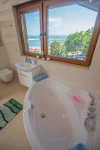 een badkamer met een wit bad en een raam bij Breeze Guest House in Chernomorets