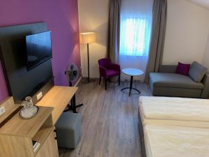 a room with a bed and a couch and a tv at Pension Lindenhof in Grasbrunn