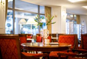 a table and chairs with a vase of flowers on it at Hotel Bellevue - Liburnia in Opatija