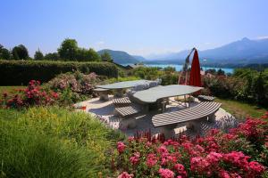 una mesa de picnic y sillas en un jardín con flores en Appartementhaus Franz Samonig, en Drobollach am Faakersee