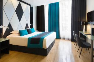 a hotel room with a bed, desk, chair, and nightstand at L'Empire Paris in Paris