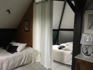 a bedroom with two beds with curtains in it at Le manège du silence in Bénesville