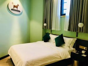a bedroom with a white bed with green walls at Moon and Chalice Boutique Hotel in Kunming