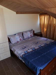 a bedroom with a bed with a blue comforter at Koura Nahla Apartment in An Nakhlah