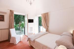 um quarto com uma cama, uma cadeira e uma janela em Casa Ponticeto em Ravello