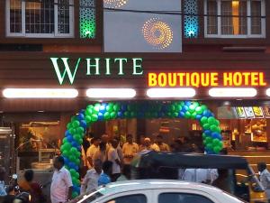 a whiteonde hotel with people walking in front of it at Hotel White Boutique in Pondicherry