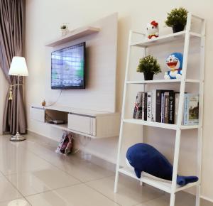 a living room with a tv and a book shelf at Batu Pahat Leisure Stay in Batu Pahat