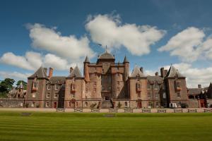 un gran castillo con un campo verde delante de él en The Maitland at Thirlestane Castle en Lauder