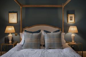 um quarto com uma cama com almofadas e 2 candeeiros em The Earl & Countess at Thirlestane Castle em Lauder