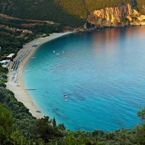 a beach with a bunch of boats in the water at LICHNOS Babis Taverna & Rooms in Parga