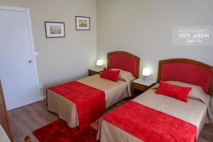 a bedroom with two beds with red pillows at Comfort Tua in Mirandela