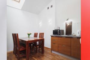een keuken met een tafel met stoelen en een magnetron bij Apartment Amaretto Długa 60 by Renters in Krakau