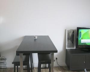 uma mesa preta com um copo ao lado de uma televisão em Studio Bastille Lappe CityCosy em Paris