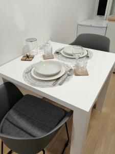 una mesa blanca con platos y vasos. en Studio apartman Adris en Šibenik