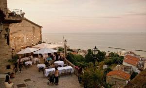 a group of tables and umbrellas with a view of the ocean at La Collina di Emma in Massignano