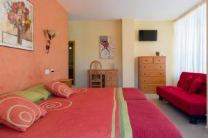 1 dormitorio con cama roja y sofá rojo en Pension Areas, en O Pindo