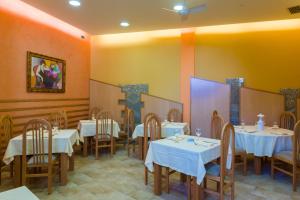a dining room with white tables and chairs and yellow walls at Pension Areas in O Pindo