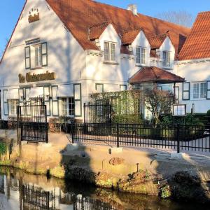 ein großes weißes Gebäude neben einem Wasserkörper in der Unterkunft De Watermolen in Kasterlee