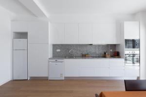 uma cozinha branca com armários e electrodomésticos brancos em Lovely Flat with Charming Terrace by Host Wise em Vila Nova de Gaia