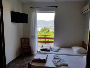 a bedroom with two beds and a large window at Kaikas Studios & Apartments in Poros