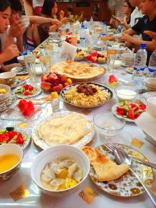 Una mesa larga con muchos platos de comida encima. en Khiva Indi Guest House, en Khiva