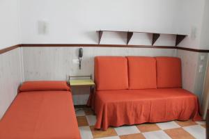 Habitación con 2 camas naranjas y teléfono en Don Paula, en Córdoba