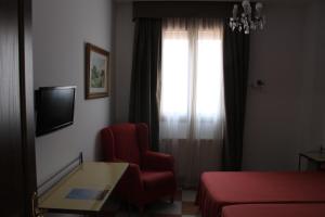 a hotel room with a red chair and a window at Don Paula in Córdoba