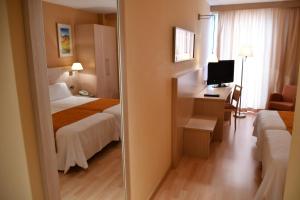 Habitación de hotel con cama y escritorio con TV. en Hotel Class Valls, en Valls