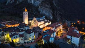 eine nachts beleuchtete Stadt mit einem Uhrturm in der Unterkunft Villa Maria in Gemona del Friuli