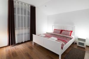 a white bed with red pillows in a bedroom at Guest House Agrodom in Nizhny Novgorod
