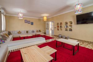 - un salon avec un canapé, des tables et une télévision dans l'établissement Riad Chebbi, à Merzouga