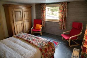 a bedroom with a bed and two chairs and a window at Chalet le Knou in Champéry