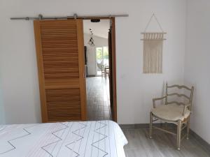 - une chambre avec un lit, une chaise et une porte dans l'établissement Le Jardin de Lucette, à Le Rouret