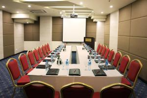 Avari Boutique Multan في ملتان: قاعة اجتماعات مع طاولة طويلة وكراسي حمراء