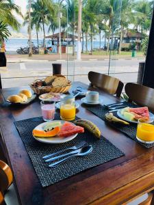 a table with a breakfast of fruit and vegetables on it at Suite Ilhaflat in Ilhabela