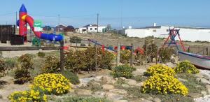 a park with a playground with a slide and flowers at Honne-Pondokkies in Hondeklipbaai