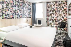 sypialnia z białym łóżkiem i ścianą pokrytą obrazami w obiekcie ibis Styles Reims Centre w mieście Reims